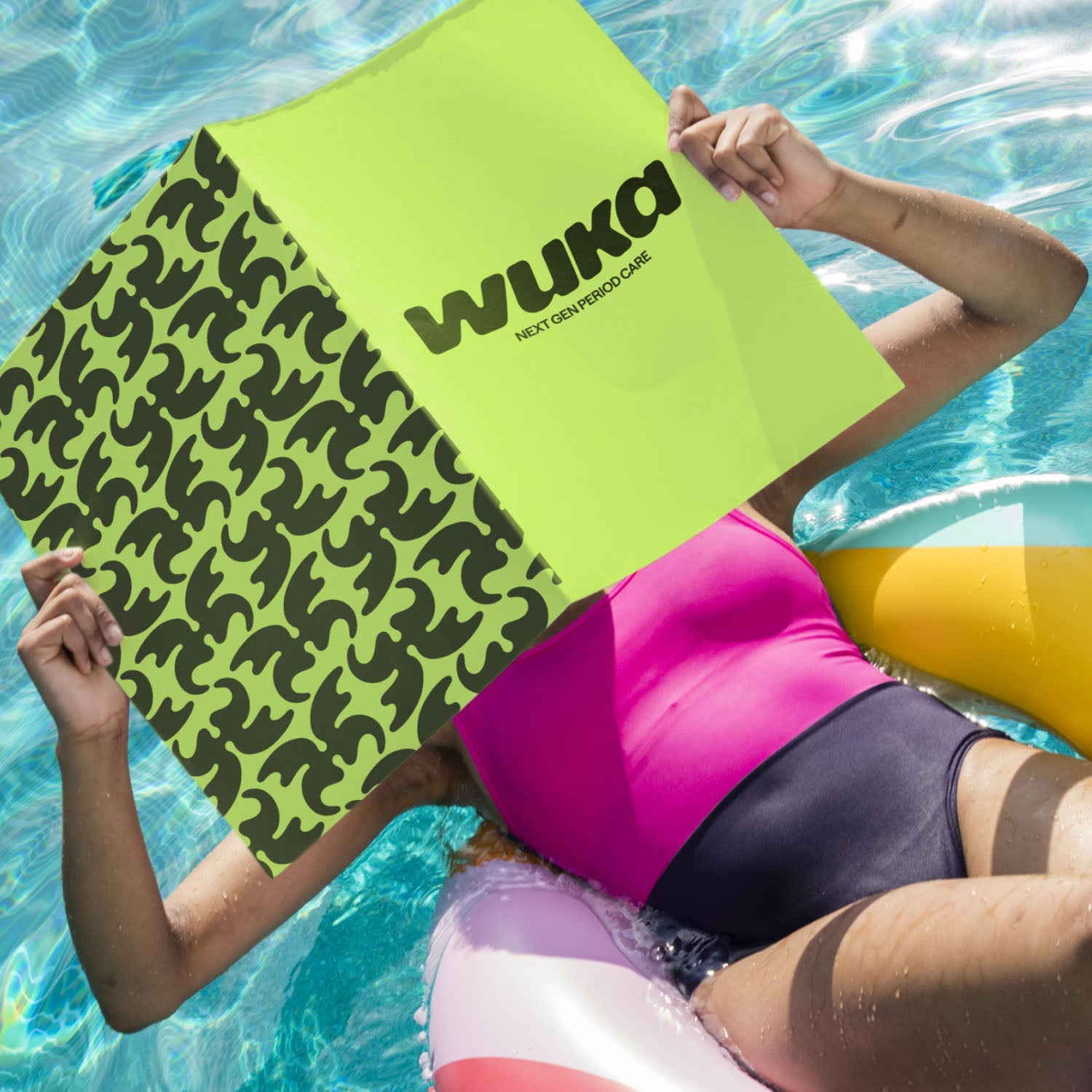 Woman relaxing on a pool float in WUKA pink and purple period-proof swimsuit, showcasing leakproof swimwear for carefree pool days.