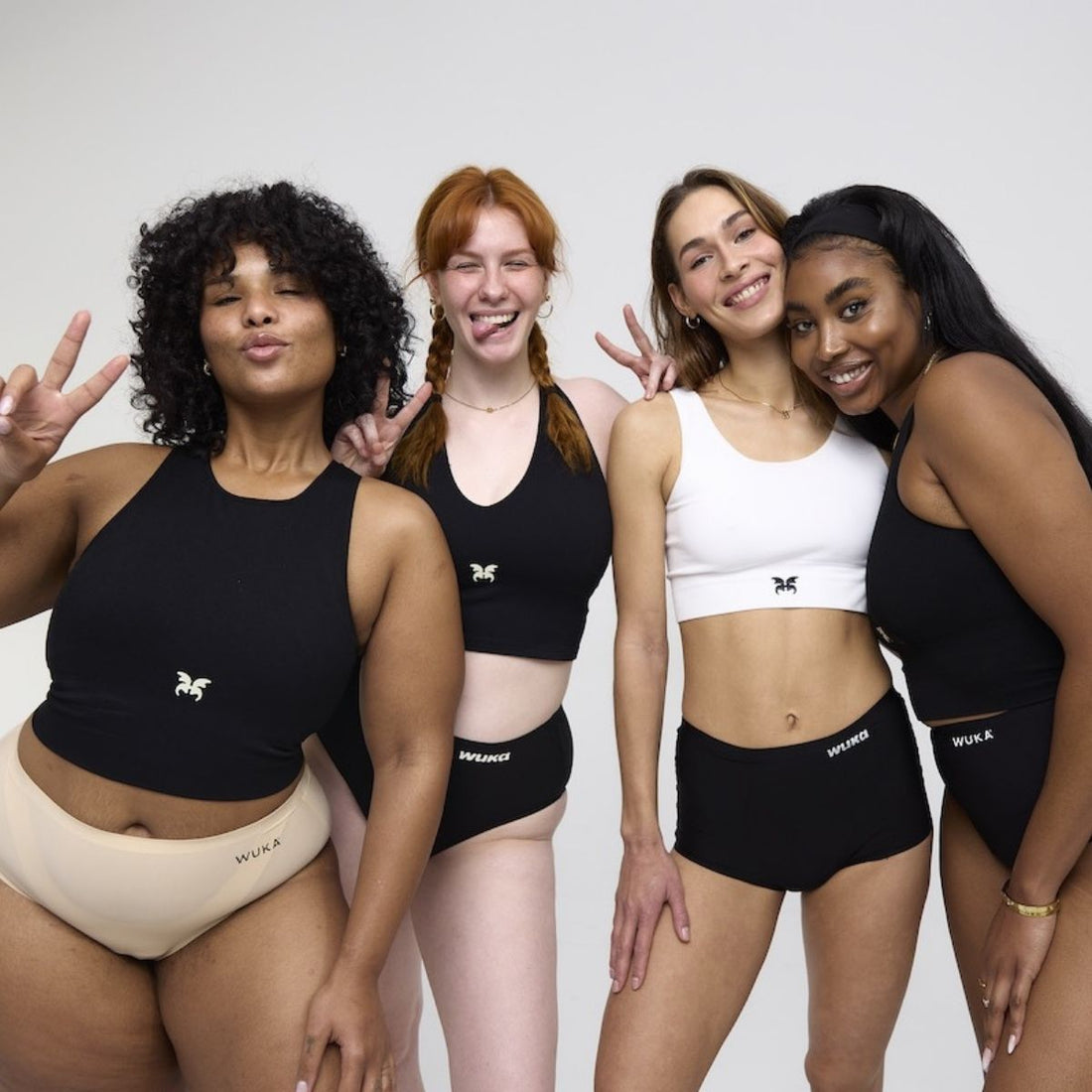 Four diverse women smiling and posing confidently in WUKA period underwear and crop tops, showing comfort, body positivity, and sisterhood.