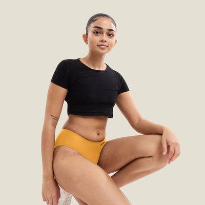 Model wearing WUKA limited edition orange Teen Stretch Seamless Midi Brief for heavy flow periods. Comfortable, leak-proof period underwear for teens.