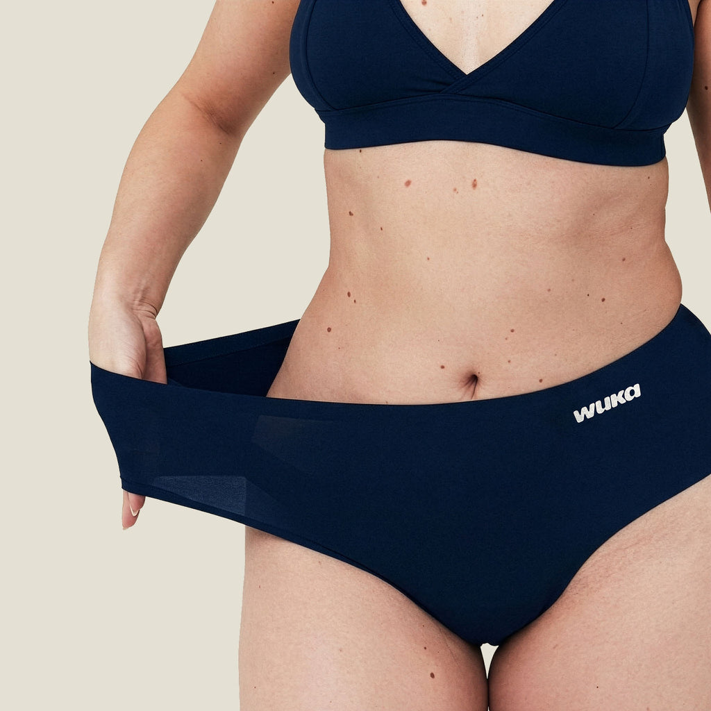 Close-up of model stretching waistband of WUKA Stretch™ Navy Midi Brief, demonstrating flexible sizing and comfort