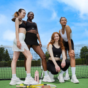 Group of girls wearing WUKA period underwear on a tennis court, showing teamwork and confidence in sport during periods